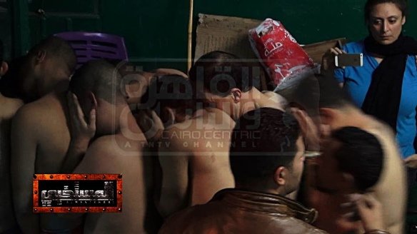 Mona Iraq, upper right, films her stripped victims being led to police wagons, December 7, 2014. Later that night she posted this photo on her Facebook page.